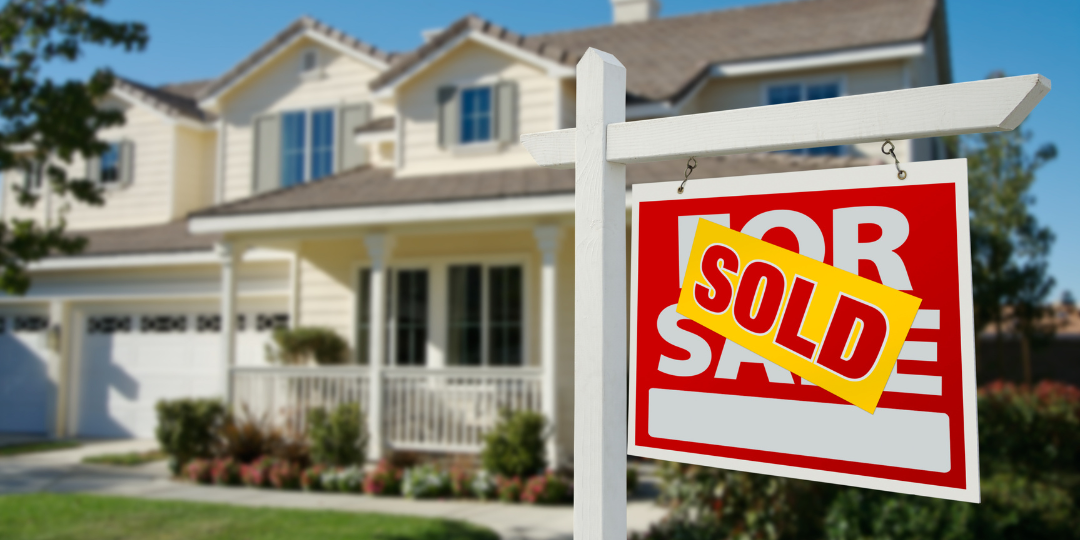 For sale sign in front of house with SOLD stamped across the front